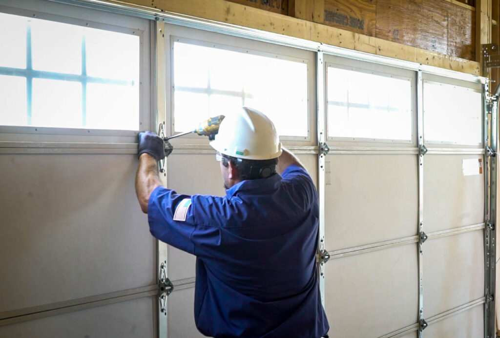 A man in a hardhat repairing a garage door