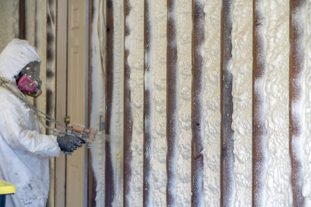 Person spraying foam insulation on wall